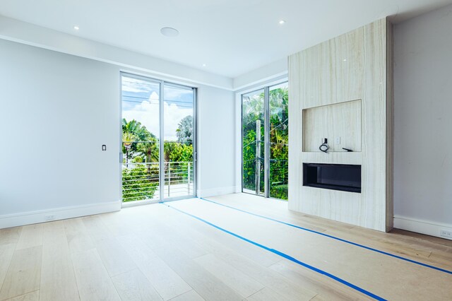 unfurnished living room with a large fireplace, baseboards, wood finished floors, and recessed lighting