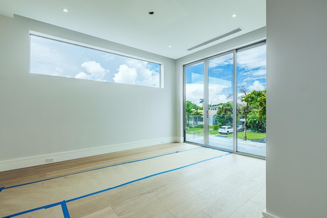 unfurnished room with baseboards, visible vents, and wood finished floors