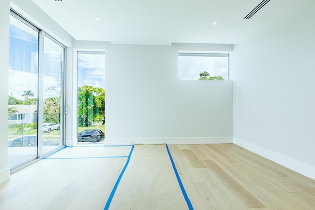 empty room featuring wood finished floors, visible vents, and baseboards