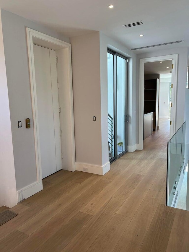 hall with light wood-style flooring, recessed lighting, visible vents, an upstairs landing, and baseboards