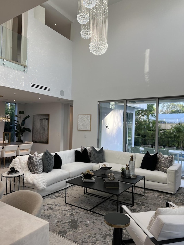 living room featuring visible vents, a towering ceiling, and an inviting chandelier