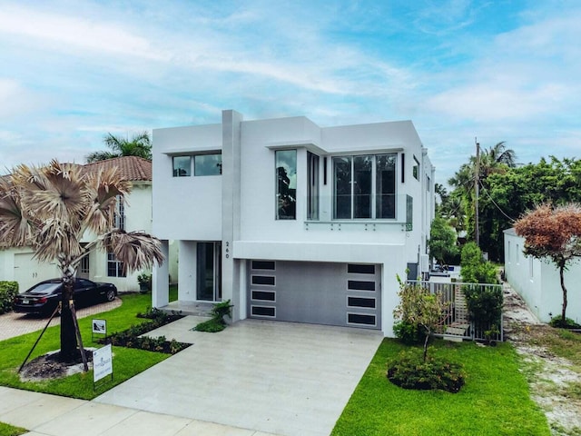 view of front of home featuring a front yard, concrete driveway, fence, and stucco siding