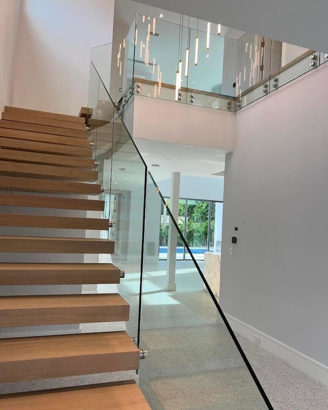 stairway with speckled floor, a towering ceiling, and baseboards