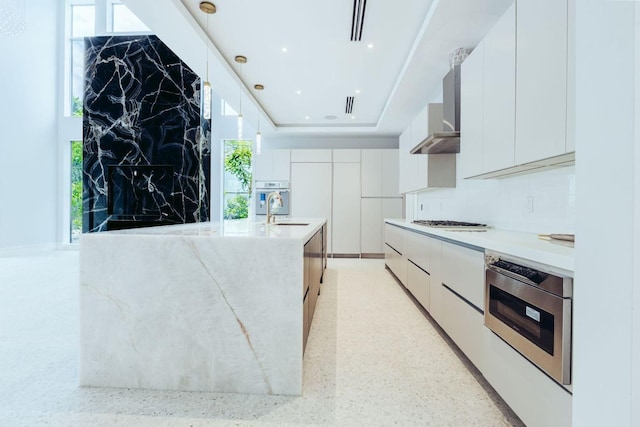 kitchen featuring wall oven, wall chimney exhaust hood, modern cabinets, and white cabinets