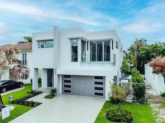 view of front of house featuring an attached garage, fence, concrete driveway, and stucco siding