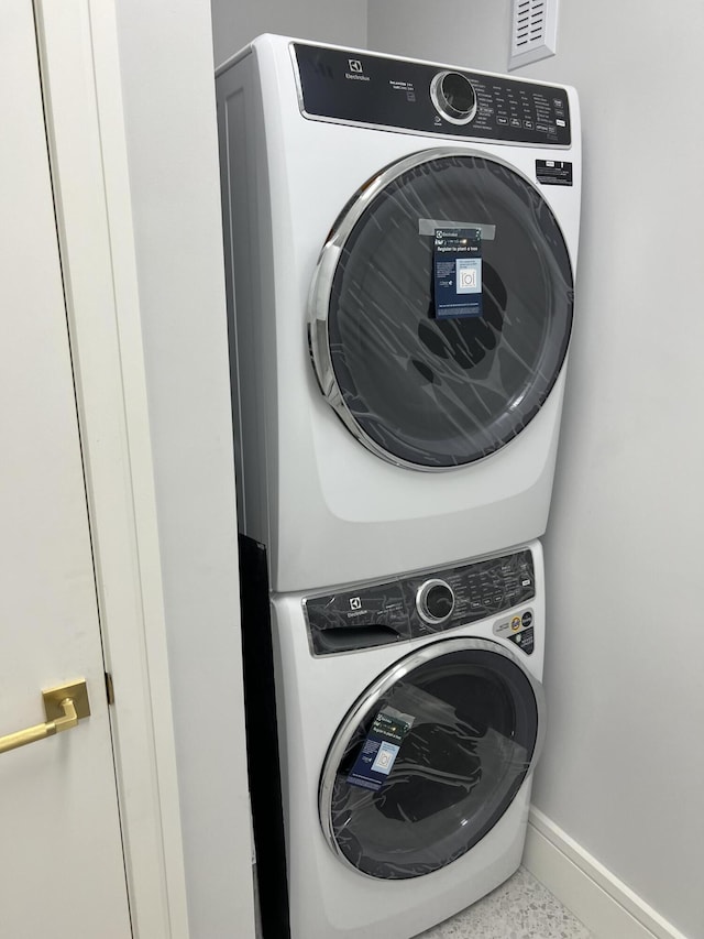 laundry room featuring laundry area, baseboards, and stacked washer / drying machine