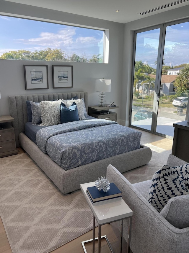 bedroom with access to outside, multiple windows, and wood finished floors