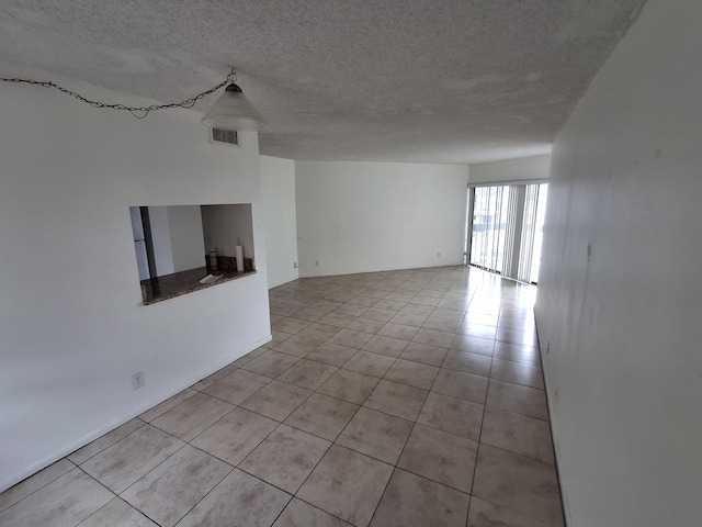 unfurnished living room featuring a textured ceiling and light tile patterned flooring