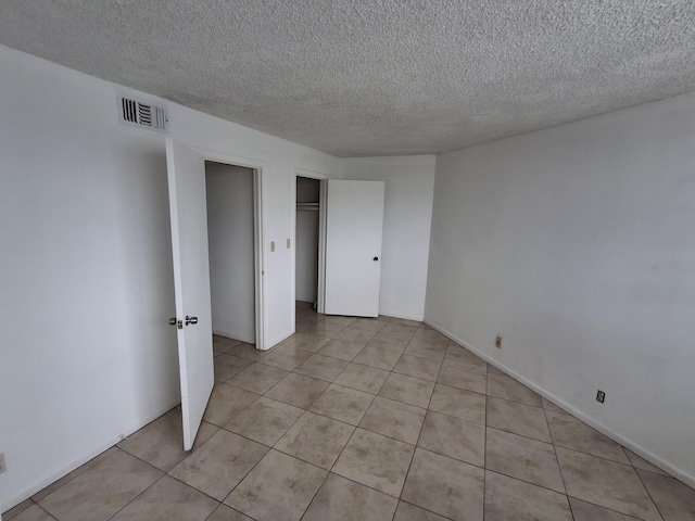 unfurnished bedroom featuring a textured ceiling and light tile patterned floors