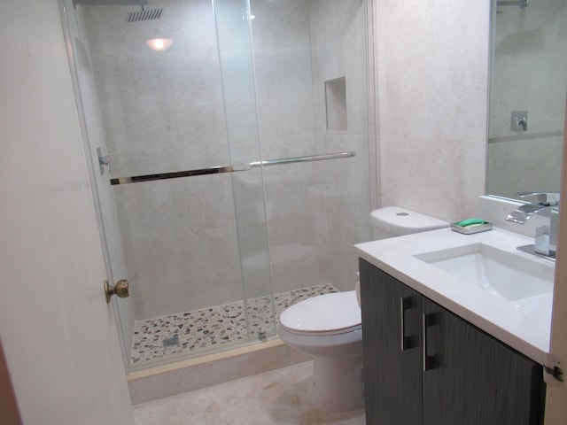 bathroom with a shower with door, vanity, tile walls, and toilet