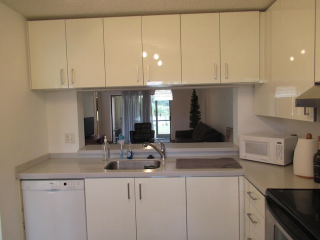 kitchen with white cabinetry, sink, wall chimney range hood, and white appliances