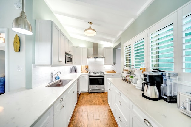 kitchen with appliances with stainless steel finishes, sink, decorative light fixtures, backsplash, and wall chimney exhaust hood