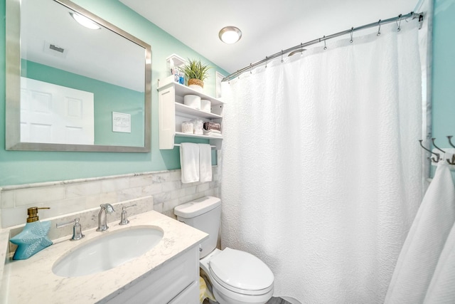 bathroom featuring vanity, toilet, walk in shower, and tile walls