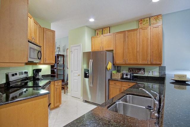 kitchen featuring sink, dark stone countertops, appliances with stainless steel finishes, and light tile patterned flooring