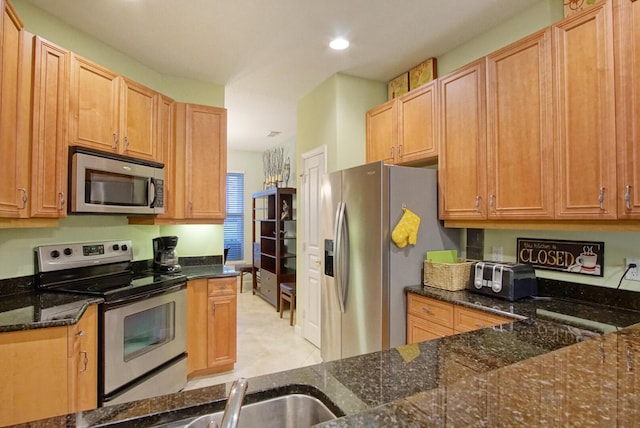 kitchen featuring sink, appliances with stainless steel finishes, and dark stone countertops