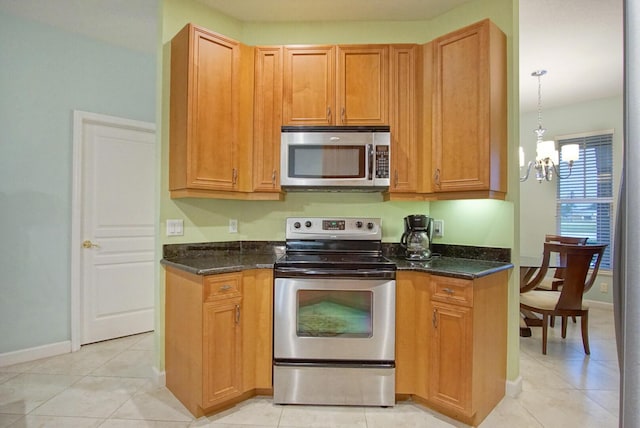 kitchen with stainless steel appliances, dark stone counters, hanging light fixtures, and light tile patterned floors