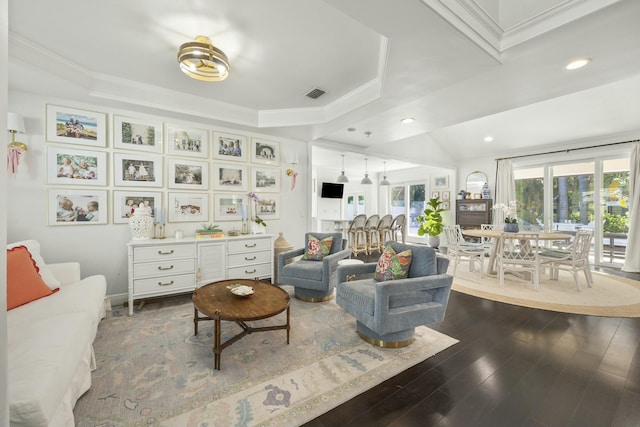 living room with hardwood / wood-style flooring, crown molding, and a raised ceiling