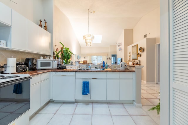 kitchen with pendant lighting, vaulted ceiling, white cabinetry, white appliances, and decorative backsplash