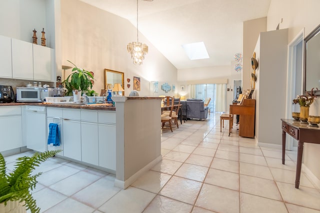 kitchen with pendant lighting, lofted ceiling with skylight, white cabinets, white appliances, and decorative backsplash