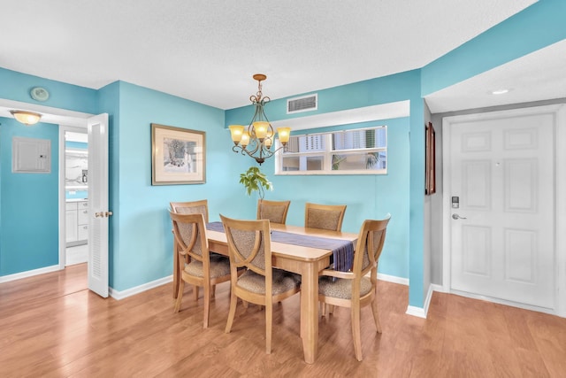 dining space with a chandelier, light hardwood / wood-style flooring, and a textured ceiling