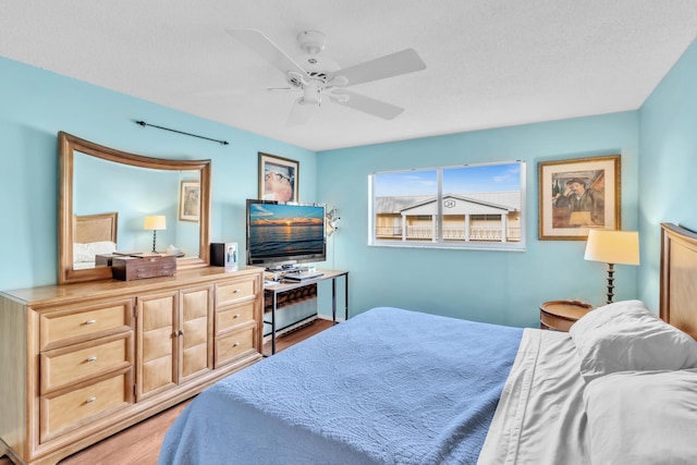 bedroom with a textured ceiling, light hardwood / wood-style floors, and ceiling fan