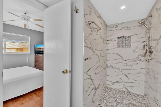 bathroom featuring hardwood / wood-style flooring, a tile shower, and ceiling fan