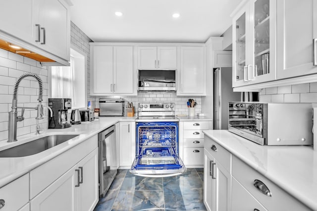 kitchen with sink, beverage cooler, white cabinets, backsplash, and stainless steel appliances