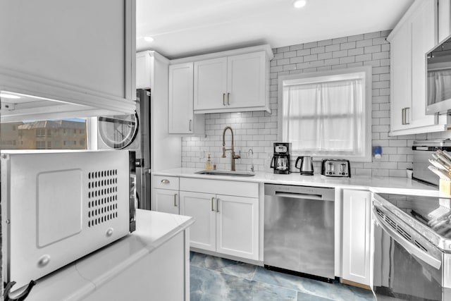 kitchen with sink, backsplash, white cabinets, and appliances with stainless steel finishes