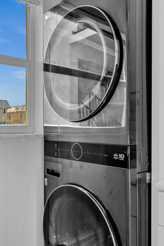 clothes washing area with stacked washing maching and dryer