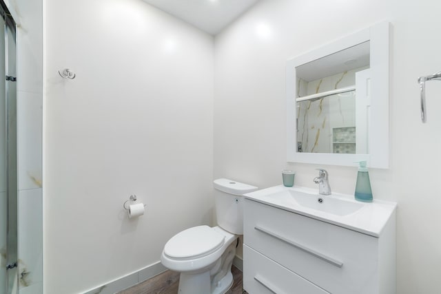 bathroom with vanity, toilet, a shower with door, and hardwood / wood-style floors