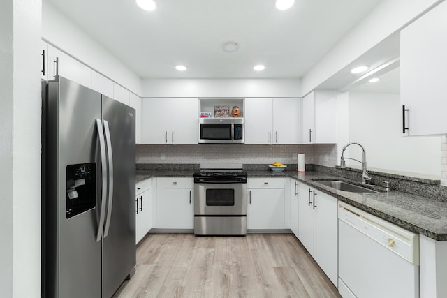 kitchen with appliances with stainless steel finishes, light hardwood / wood-style floors, sink, and white cabinets