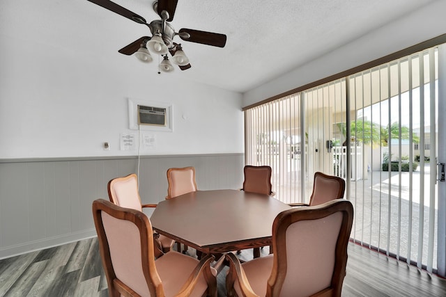 dining room with hardwood / wood-style flooring, a healthy amount of sunlight, a wall mounted AC, and a textured ceiling