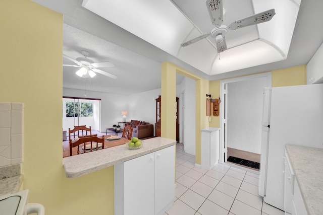 kitchen featuring ceiling fan, light tile patterned floors, white fridge, and white cabinets