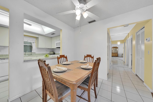 tiled dining space featuring ceiling fan, sink, and a textured ceiling