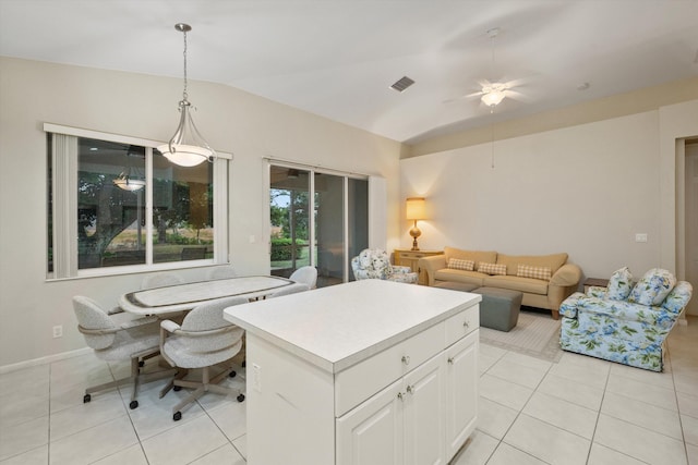 kitchen with vaulted ceiling, a kitchen island, pendant lighting, white cabinets, and light tile patterned floors