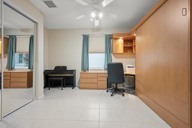 home office with built in desk, ceiling fan, and light tile patterned floors