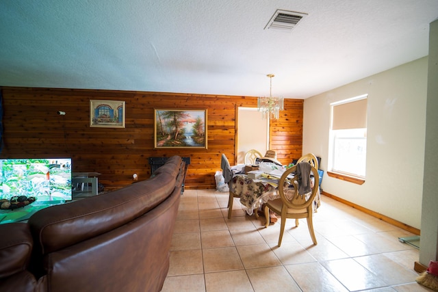 dining area with wooden walls, baseboards, visible vents, an inviting chandelier, and a textured ceiling