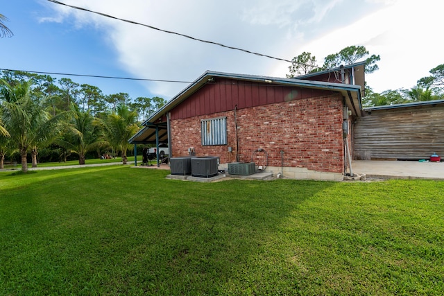 view of side of property featuring central AC unit, a lawn, and brick siding