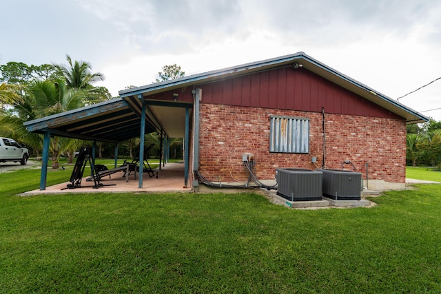 view of side of property featuring brick siding, a yard, and central AC unit