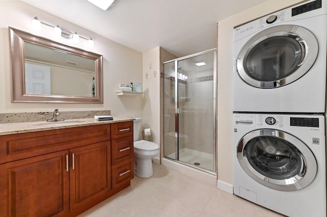 bathroom with stacked washing maching and dryer, a shower with shower door, vanity, toilet, and tile patterned floors