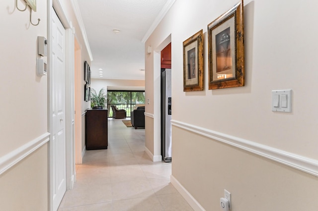 hall with ornamental molding and light tile patterned floors