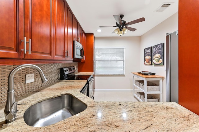 kitchen featuring sink, light stone counters, appliances with stainless steel finishes, ceiling fan, and backsplash