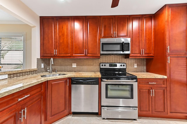 kitchen with light stone counters, appliances with stainless steel finishes, sink, and backsplash