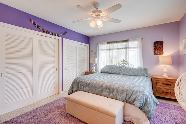 bedroom featuring ceiling fan, light colored carpet, and two closets