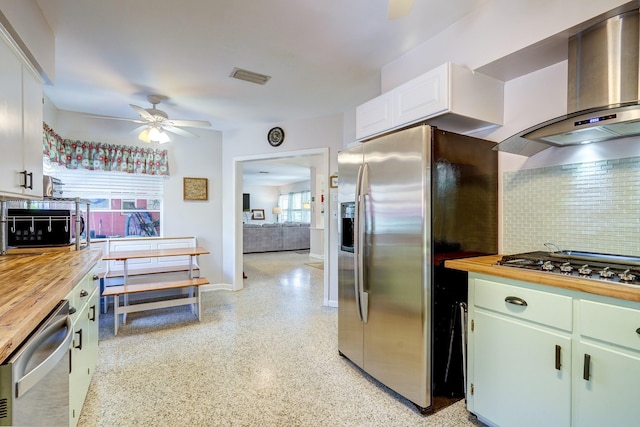 kitchen featuring white cabinets, extractor fan, stainless steel appliances, ceiling fan, and butcher block countertops