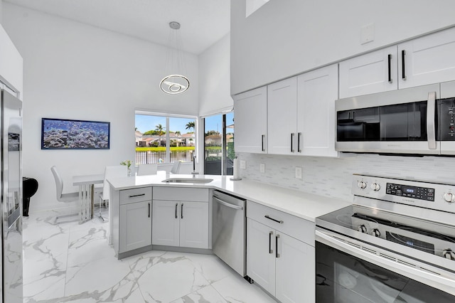 kitchen featuring hanging light fixtures, appliances with stainless steel finishes, sink, a water view, and a towering ceiling