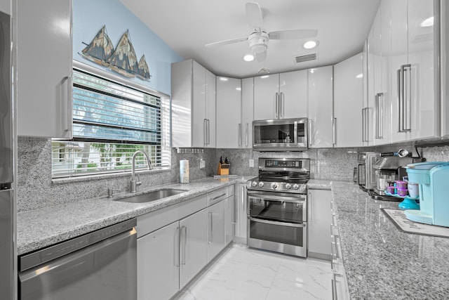 kitchen with sink, light stone counters, white cabinetry, and stainless steel appliances