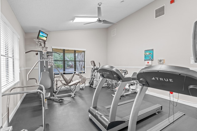 exercise room with ceiling fan, plenty of natural light, a textured ceiling, and lofted ceiling