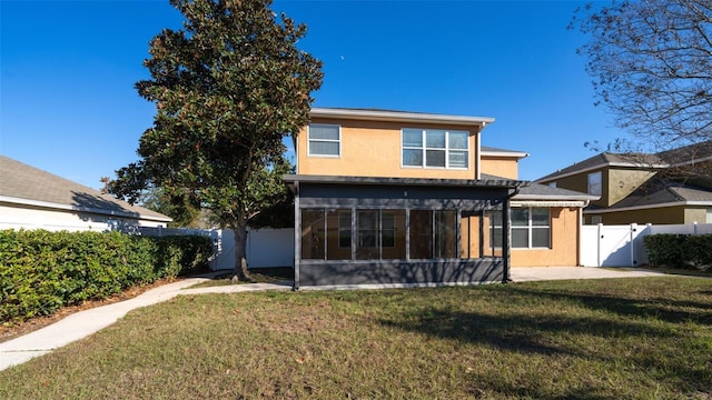 rear view of house featuring a sunroom and a lawn