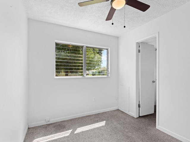 carpeted empty room featuring ceiling fan and a textured ceiling